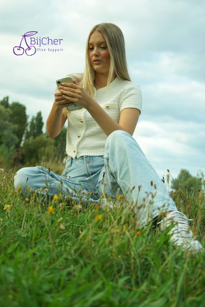 Jonge dame op smartphone in het lente gras
